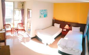 a bedroom with two beds and a table and chairs at Royal Holiday Imv in Baihe