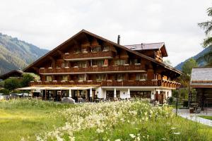 duży drewniany budynek na polu kwiatów w obiekcie Hotel Alpenland w mieście Gstaad