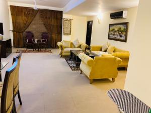 a living room with yellow couches and chairs at Royal Two Bed Luxury Apartment Gulberg in Lahore