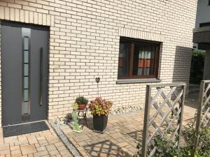 a brick house with a door and two potted plants at Ferienwohnung -Zur Sonnenleite- in Dörfles-Esbach