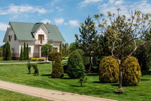 a house with a green yard with trees and bushes at Рестпарк рекреаційний комплекс in Luts'k