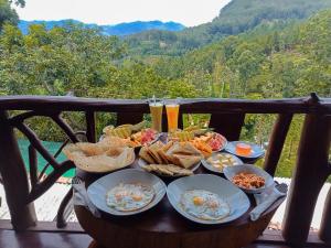 a table full of food on a balcony with mountains in the background at CHILL Wood ELLA in Ella