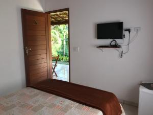 a bedroom with a bed and a tv on the wall at Pouso Familiar - Cantinho das Águas in Paraty