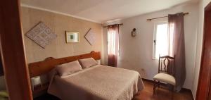 um quarto com uma cama, uma janela e uma cadeira em La Hoyilla Hostel - La Aldea em San Nicolás