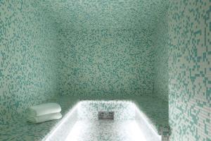 a bathroom with a bath tub with green tiles at Heliopic Hotel & Spa in Chamonix