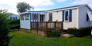 a small white house with a wooden deck at omaha beach home in Colleville-sur-Mer