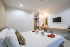 a bedroom with a white bed with white pillows and a tv at Wanarom Residence Hotel in Krabi town