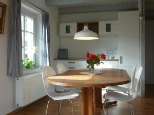 a dining room table with white chairs and a vase with red flowers at Schlei-Rose in Schaalby