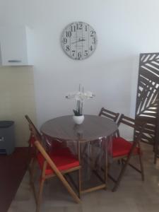 une table à manger et des chaises avec une horloge sur le mur dans l'établissement BRILOC Appartement Route des îles Sanguinaires, à Ajaccio