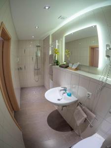 ein Bad mit einem Waschbecken und einem Spiegel in der Unterkunft Hotel - Restaurant - Metzgerei Sonne in Loffenau