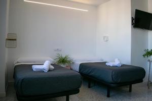 een kamer met 2 bedden en 2 poeven bij Alojamientos Teatro in Porcuna