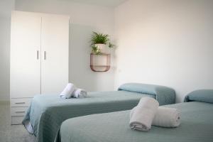 una habitación con 2 camas y una planta en la pared en Alojamientos Teatro, en Porcuna