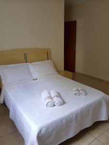 Una cama blanca con tres toallas enrolladas. en Casa da Cachoeira, en Brotas