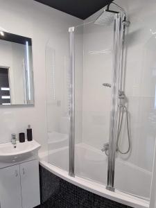 uma casa de banho branca com um chuveiro e um lavatório. em Apartament Panoramiczna em Kielce