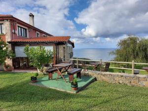 une maison avec une table de pique-nique et une vue sur l'océan dans l'établissement Posada Punta Liñera, à San Vicente de la Barquera