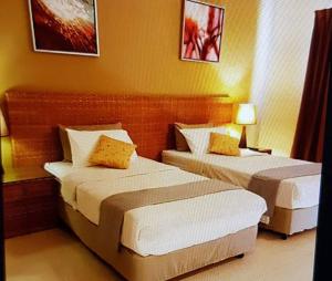 2 bedden in een hotelkamer met gele muren bij Gold Coast Morib Resort Apartment Ezzy in Kampong Tanjong Pechah