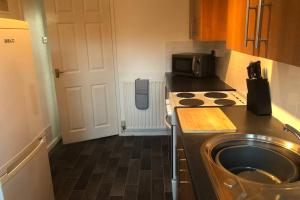 a small kitchen with a stove and a microwave at Newton Aycliffe Contractors Accommodation in Newton Aycliffe