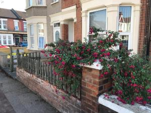 a brick fence with pink flowers in front of a house at Richmond Luxury flat Fabulous location in Southend-on-Sea
