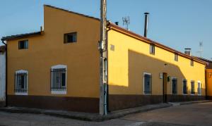 żółty budynek z przeszklonymi oknami na ulicy w obiekcie Casa Rural Ruplas w mieście Villalba de Adaja