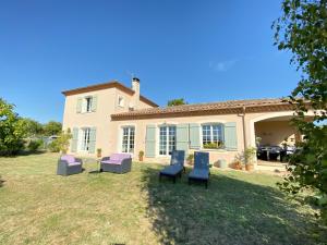 una casa con un patio con sillas azules y moradas en Chambre avec sa salle de bain privée attenante et wc privé en Larroque-sur-lʼOsse