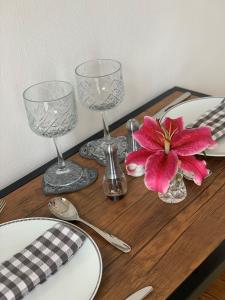 a table with two wine glasses and a pink flower on it at Little Haven in Dartmouth