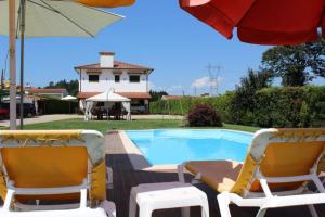 吉馬良斯的住宿－CORVITINHO，游泳池旁的两把椅子和一把遮阳伞