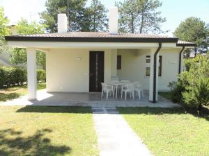 a small white house with a table and chairs at Villaggio Azzurro - Ville in Bibione