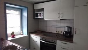 a kitchen with white cabinets and a stove top oven at Ferienwohnung Louise in Klingenthal