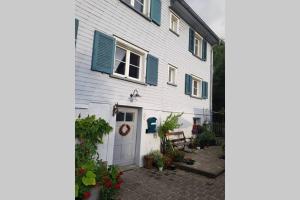 a white house with blue shutters and a patio at Ferienwohnung am Hatler Brunnen in Dornbirn