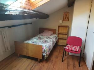 a bedroom with a bed and a red chair at Domaine du Plan del Poux Gîte rural in Combret
