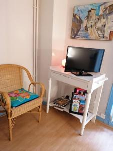 escritorio blanco con TV y silla en Chambre d'hôtes Les Myriades D'Or en Regny