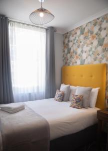 Paddington Park Hotel في لندن: غرفة نوم بسرير مع اللوح الأمامي الأصفر ونافذة