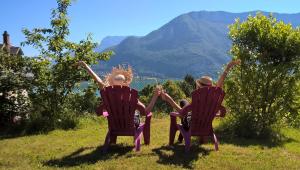 deux personnes assises sur des chaises dans un champ avec des montagnes en arrière-plan dans l'établissement Auberge de Jeunesse HI Annecy, à Annecy