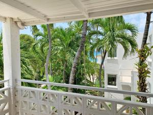 a white porch with palm trees in the background at Sand Castle on the Beach - Adults Only in Frederiksted