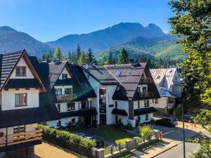 un groupe de maisons avec des montagnes en arrière-plan dans l'établissement Apartamenty Inny Świat Zakopane, à Zakopane