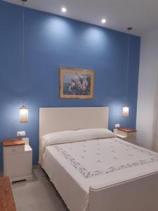 a blue bedroom with a white bed and a blue wall at Casa Vacanze RoSa in Acitrezza