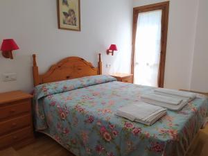 a bedroom with a bed with a floral bedspread at Apartamentos Ball Benas Edificio Mirador in Cerler