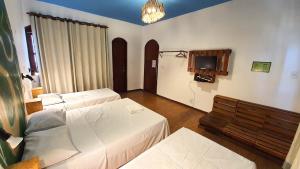 a hotel room with two beds and a tv at Local Hostel & Suites Manaus in Manaus