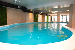 a large swimming pool with blue water in a building at Hotel Diamond Prishtina in Prishtinë