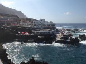 a view of a beach with the ocean and buildings at Pensão Fernandes in Porto Moniz