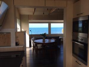 een keuken en eetkamer met een tafel en uitzicht op de oceaan bij Nouvelle Vague in Bretteville