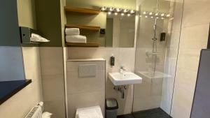 a bathroom with a toilet, sink, and shower at Munich Rooms Hotel in Munich