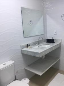 a bathroom with a sink and a toilet and a mirror at Sorrento Suítes Maragogi a 3 min da Orla in Maragogi