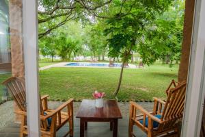 porche con mesa, sillas y piscina en Tranquil Wild, en Tanamalwila