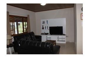 a living room with two black leather couches and a television at Sítio Pousada Cio da Terra in Lumiar
