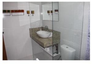 a white bathroom with a sink and a toilet at Sítio Pousada Cio da Terra in Lumiar