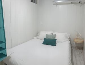 a white bed with a blue pillow on it at Casa do Pátio in Lisbon