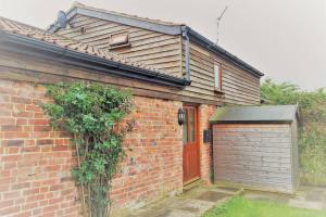 a brick house with a garage and a red door at The Old Cowshed Annexe in Taunton