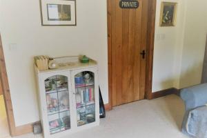 a living room with a book shelf with items on it at The Old Cowshed Annexe in Taunton