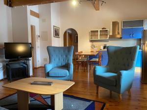 uma sala de estar com duas cadeiras azuis e uma televisão em Villa Santer em Dobbiaco
